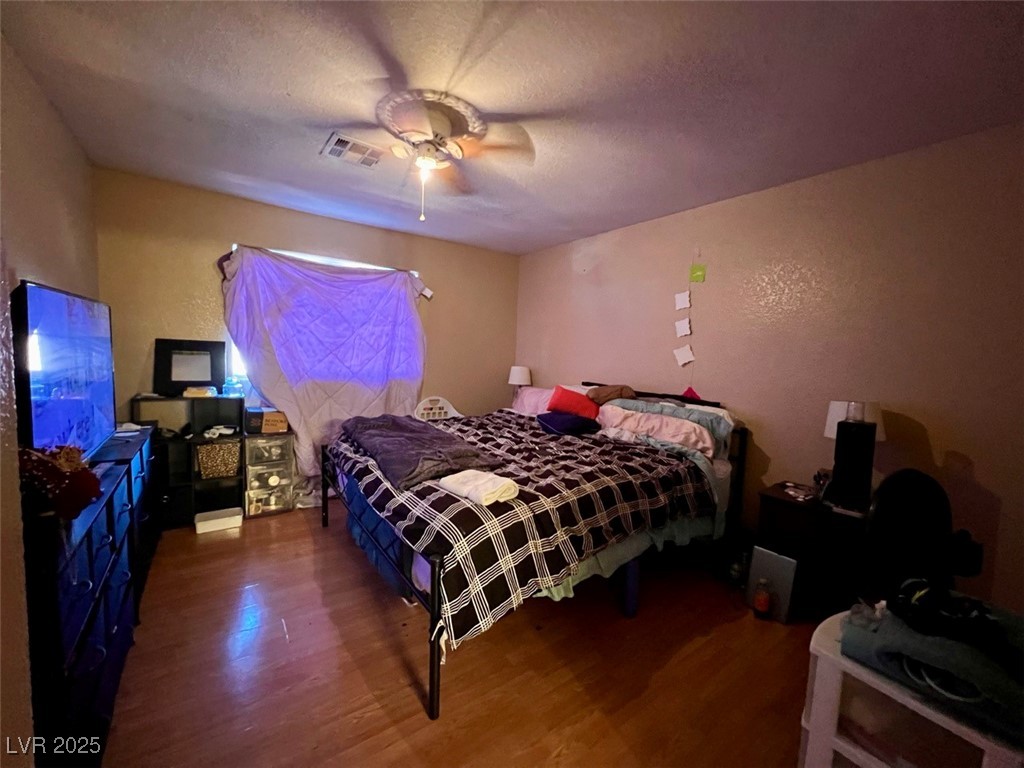 4730 East Craig Road, Unit 2071 Las Vegas, NV 89115 - Photo 9 of 23 Bedroom featuring a textured ceiling, a textured wall, wood finished floors, and ceiling fan