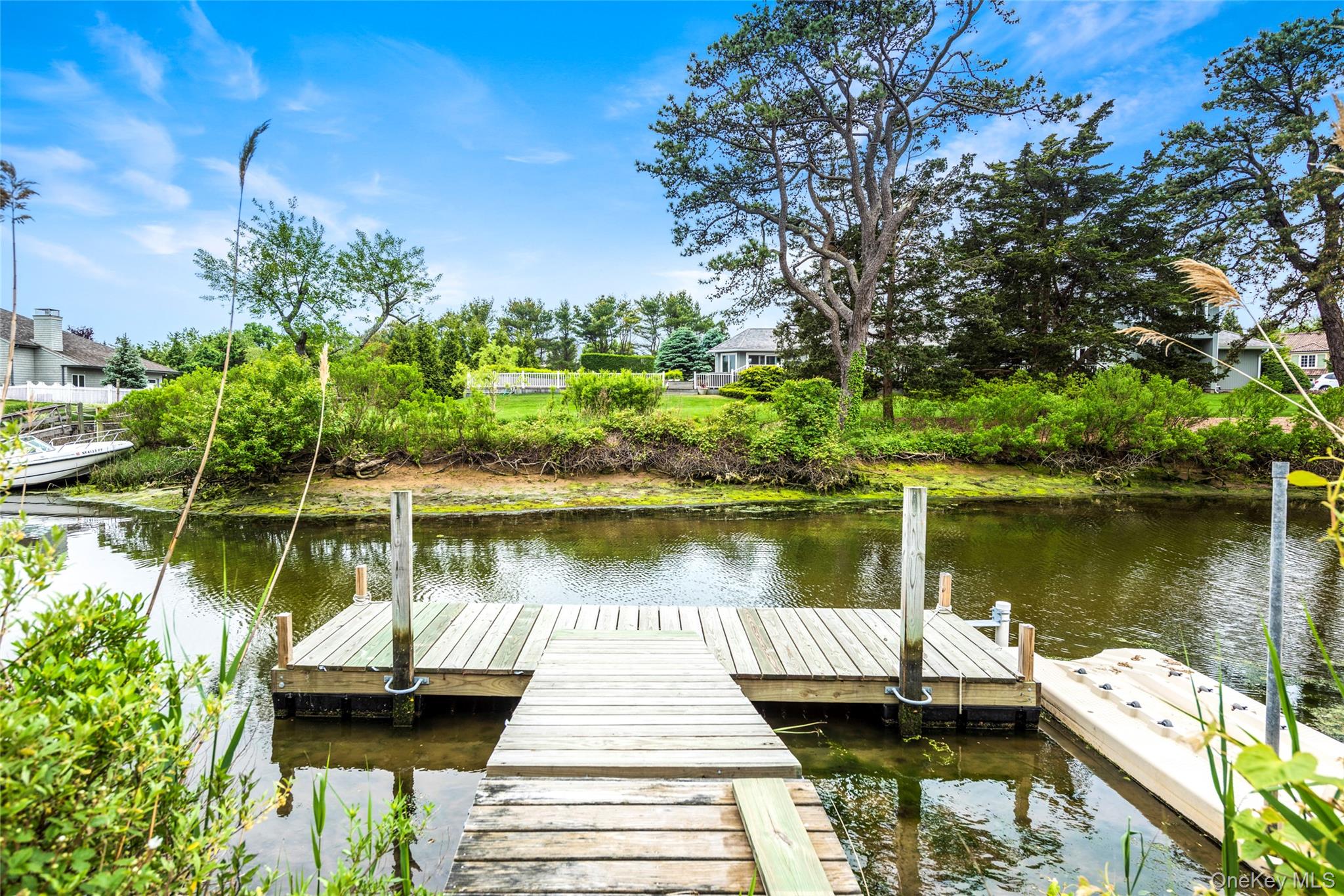 5 Woodcock Lane Remsenburg, NY 11960 - Photo 23 of 23 a lake view with a wooden bridge and lake view