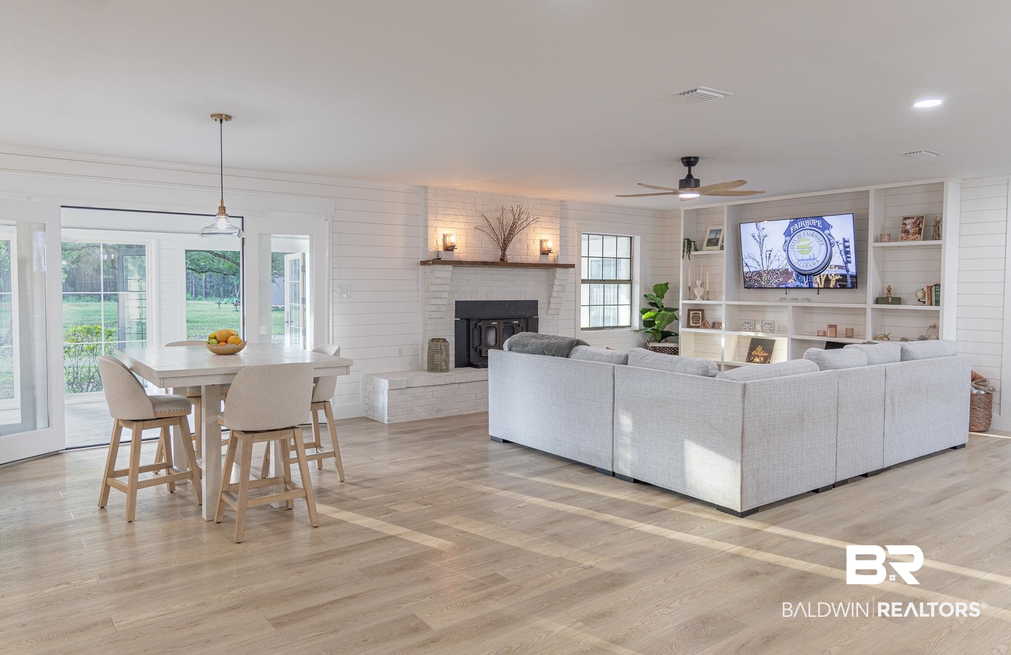Living room with a fireplace, light wood finished floors, and a ceiling fan