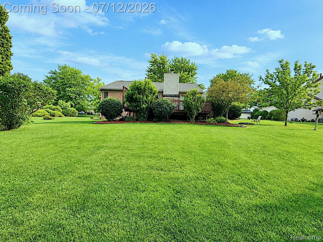 2033 Avonstoke Road Rochester, MI 48307 - Photo 23 of 26 Expansive green lawn with established landscaping surrounding a rear wood deck and brick exterior