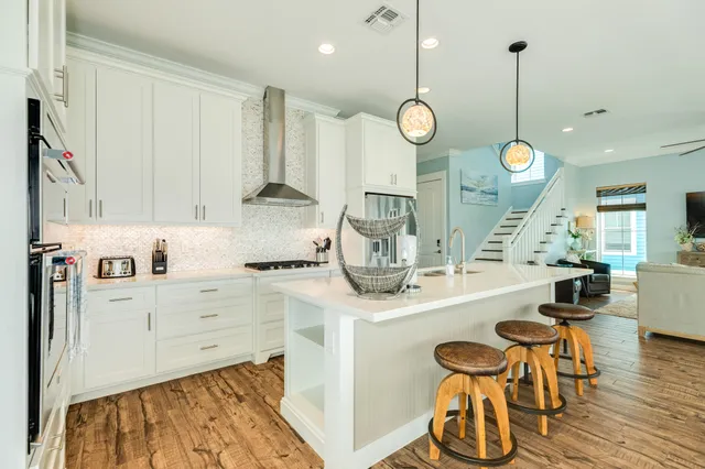 a kitchen with stainless steel appliances granite countertop a sink a stove and a wooden floors