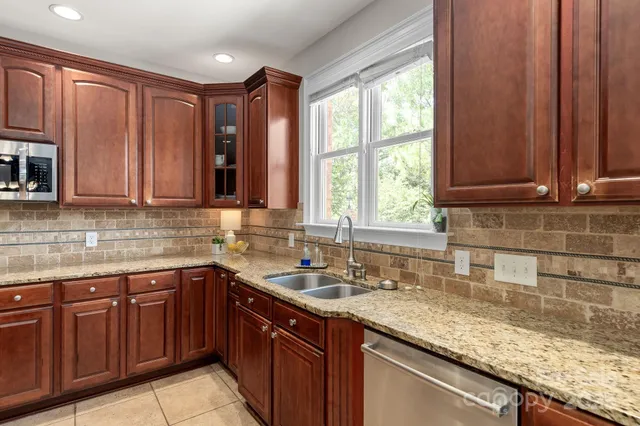 a kitchen with stainless steel appliances granite countertop wooden cabinets a sink and dishwasher with wooden floor