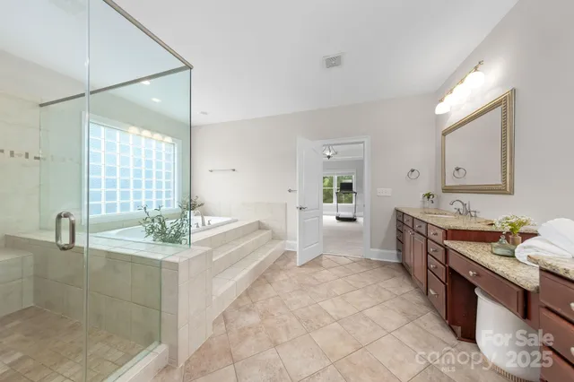 a large bathroom with a granite countertop double vanity sink a mirror and a bathtub