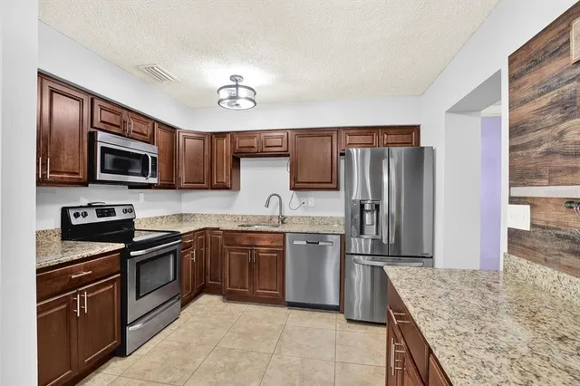a kitchen with stainless steel appliances granite countertop a stove refrigerator and microwave