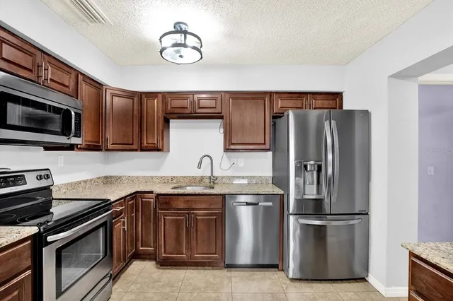 a kitchen with stainless steel appliances granite countertop a refrigerator stove top oven a sink and dishwasher