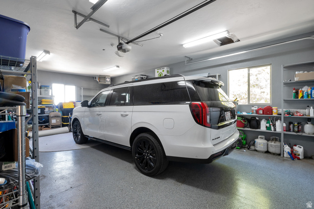 513 Southfork Drive Draper, UT 84020 - Photo 69 of 70 Spacious garage featuring a durable epoxy floor, overhead fluorescent lighting, a built-in shelving system, an automatic garage door opener, and multiple windows