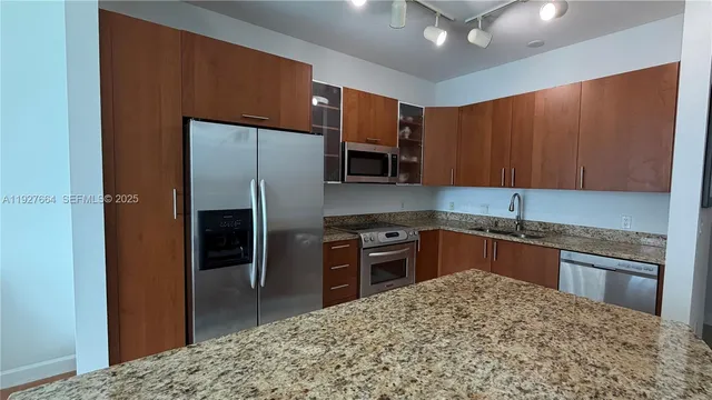 a kitchen with stainless steel appliances granite countertop a refrigerator a stove and a sink with cabinets