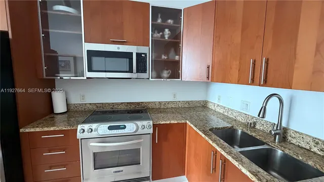 a kitchen with granite countertop a sink stainless steel appliances and cabinets