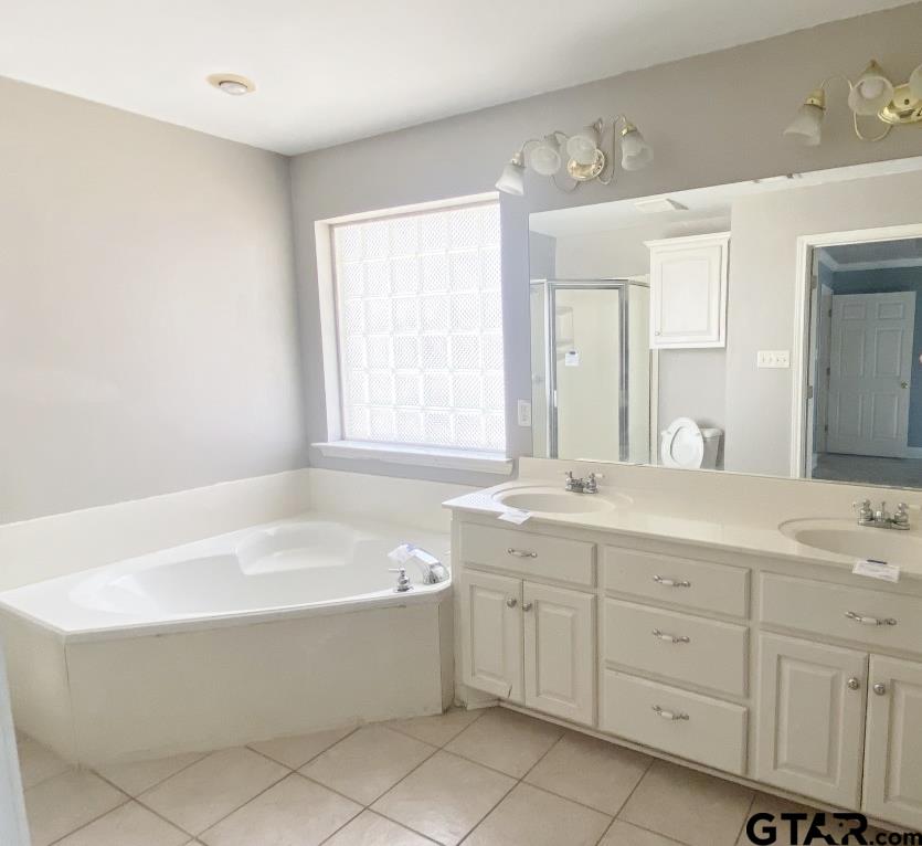 1707 Rotan Road Mount Pleasant, TX 75455 - Photo 10 of 18 a bathroom with a tub a sink double vanity and a window