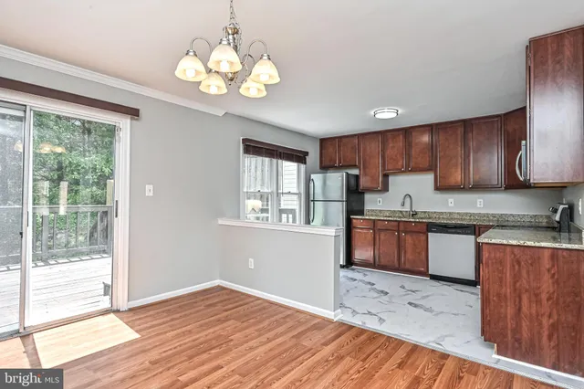 a kitchen with granite countertop wooden floors a refrigerator a stove top oven and a large window