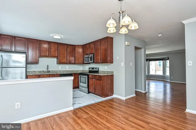 a kitchen with stainless steel appliances granite countertop wooden cabinets a stove a sink and dishwasher a refrigerator with wooden floor