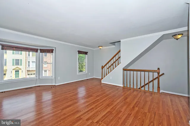 a view of an empty room with wooden floor and window