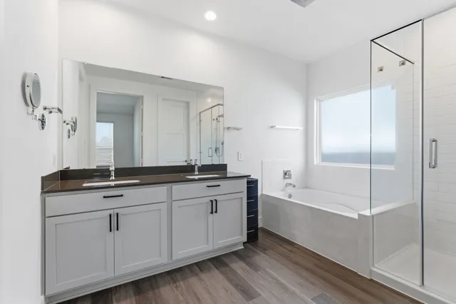 a bathroom with a double vanity sink and mirror with bathtub