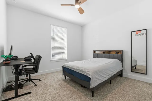 a bedroom with a bed table chair and a window