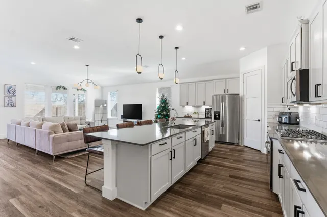 a kitchen with stainless steel appliances kitchen island hardwood floor sink and stove