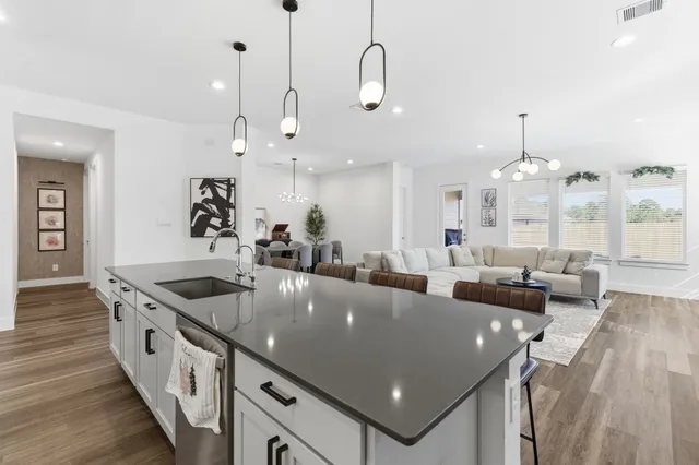 an open kitchen with stainless steel appliances granite countertop a sink a counter top space and living room view