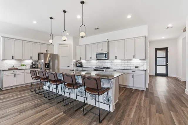 a kitchen with stainless steel appliances kitchen island granite countertop a wooden floor and white cabinets