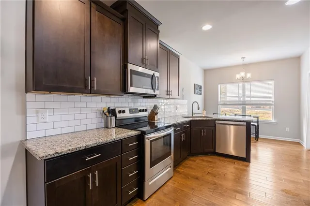 a kitchen with stainless steel appliances granite countertop wooden cabinets a stove top oven a sink and dishwasher