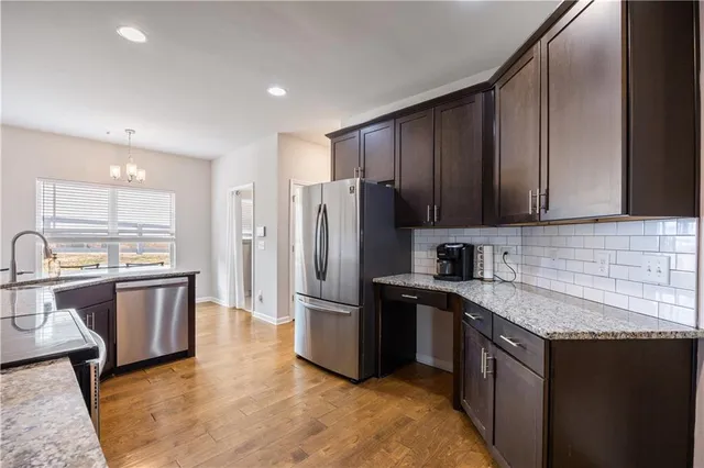 a kitchen with stainless steel appliances granite countertop a refrigerator a sink dishwasher a stove top oven a refrigerator and dishwasher