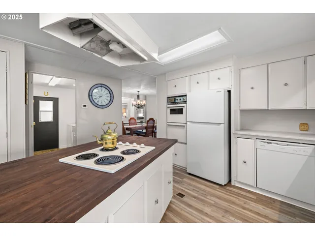 a kitchen with a refrigerator a stove top oven a clock and a window