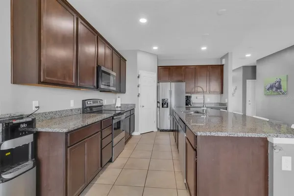 a kitchen with stainless steel appliances granite countertop a stove top oven a sink dishwasher a dining table and chairs