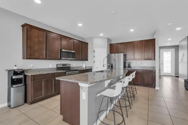 a kitchen with stainless steel appliances granite countertop a stove a sink a refrigerator with a dining table and chairs