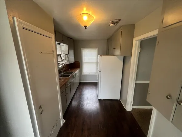 a kitchen with a refrigerator a stove and wooden floor