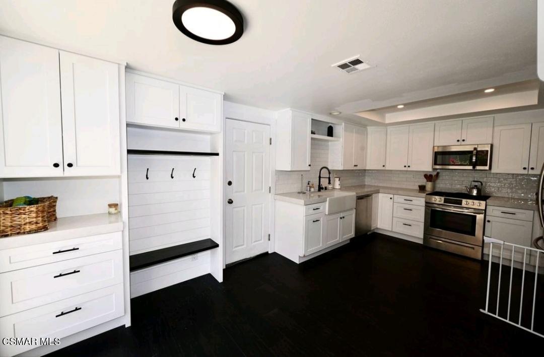 979 Thistlegate Road Oak Park, CA 91377 - Photo 10 of 19 a kitchen with white cabinets and stainless steel appliances