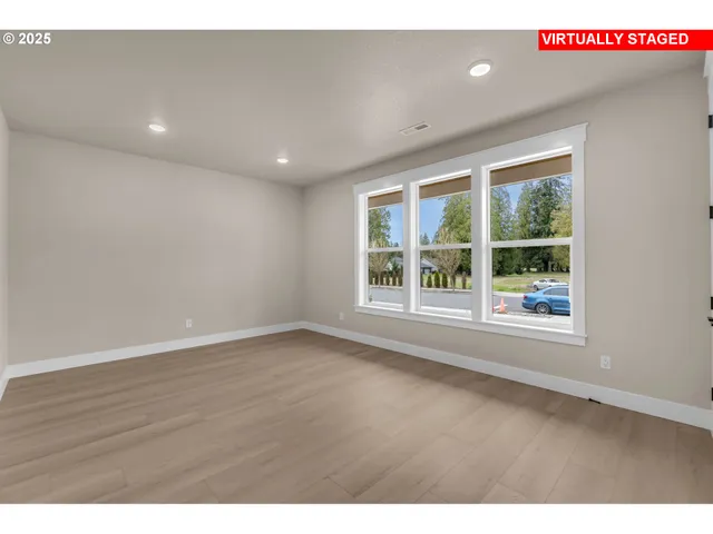 a view of an empty room with wooden floor and windows