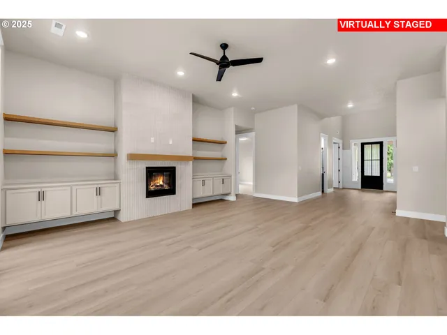 a view of an empty room with wooden floor and a kitchen