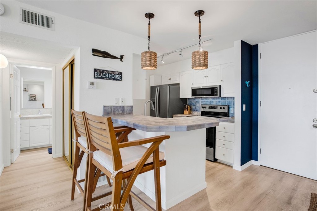 1140 East Ocean Boulevard, Unit 235 Long Beach, CA 90802 - Photo 12 of 45 a kitchen with cabinets a counter and chairs in it