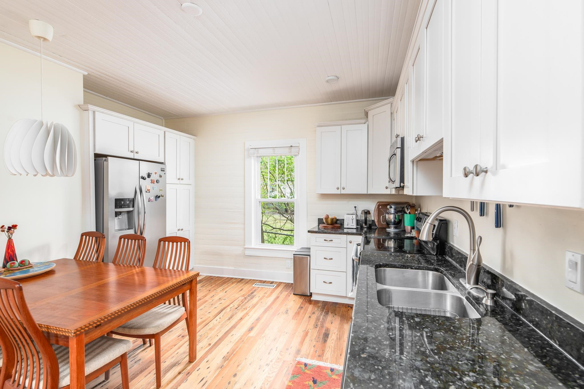 1112 Berkeley Street Durham, NC 27705 - Photo 5 of 23 a kitchen with stainless steel appliances granite countertop a stove a sink dishwasher a dining table and chairs with wooden floor