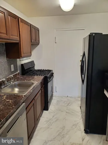 a kitchen with stainless steel appliances granite countertop a refrigerator a stove and a sink with wooden cabinets