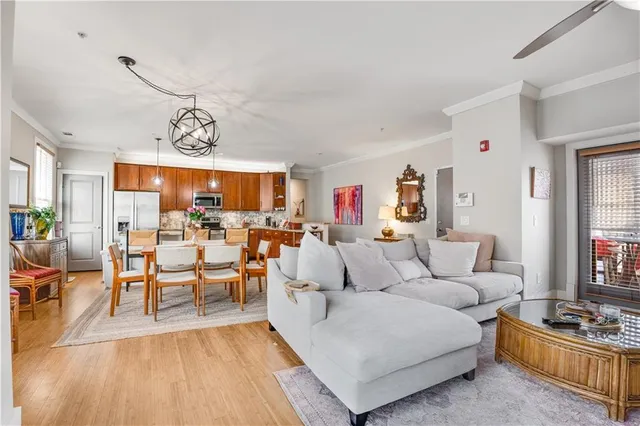 a living room with furniture kitchen view and a wooden floor