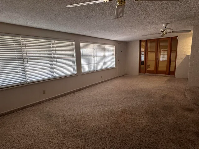 en empty room with windows and chandelier fan