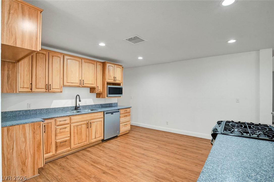 1810 Pinto Road Henderson, NV 89002 - Photo 21 of 53 A well-equipped kitchen features wooden cabinetry, stone-like countertops, and stainless steel appliances.