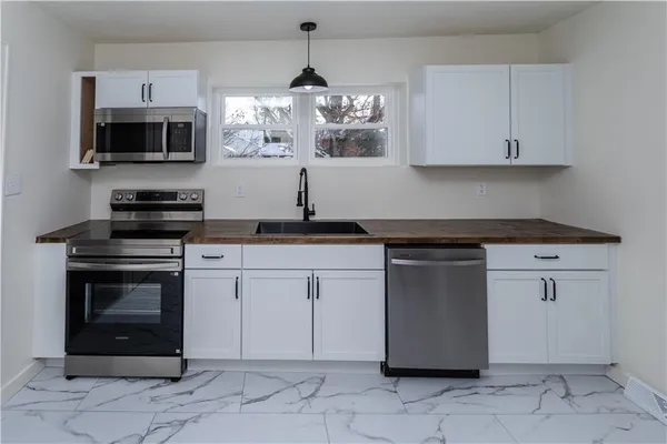 a kitchen with granite countertop white cabinets stainless steel appliances and a sink