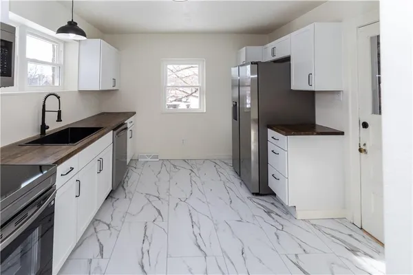 a kitchen with stainless steel appliances a stove a sink a refrigerator and cabinets