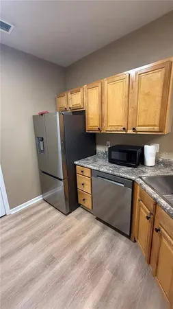 a kitchen with stainless steel appliances granite countertop a refrigerator sink and wooden cabinets