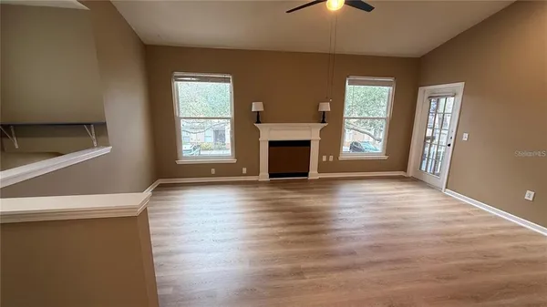 an empty room with wooden floor fireplace and windows