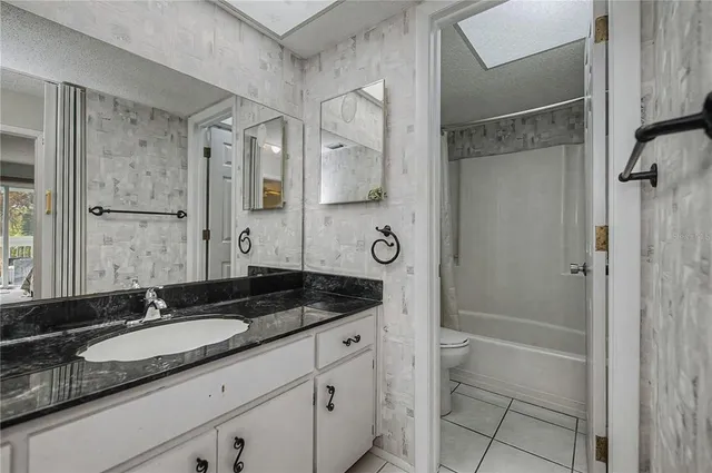 a bathroom with a granite countertop sink a toilet a mirror and shower