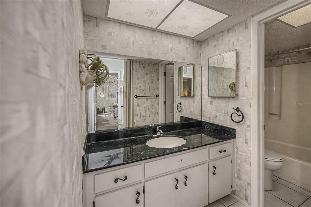 22375 Edgewater Drive, Unit 238 Punta Gorda, FL 33980 - Photo 34 of 57 a bathroom with a granite countertop sink a toilet a mirror and shower