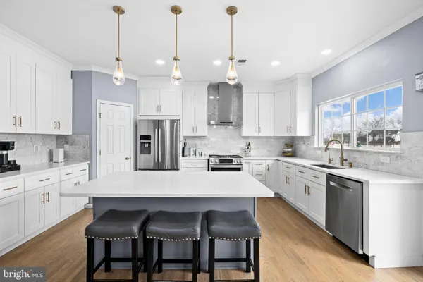 a large kitchen with stainless steel appliances kitchen island granite countertop a sink a stove a refrigerator and island with wooden floor