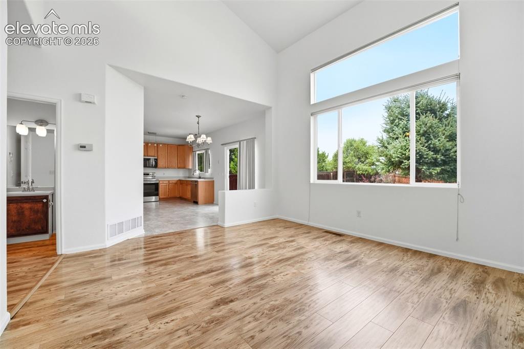 7904 Coffee Road Peyton, CO 80831 - Photo 6 of 48 Spacious room with wood-finish flooring, soaring vaulted ceilings, and a large window arrangement featuring a transom