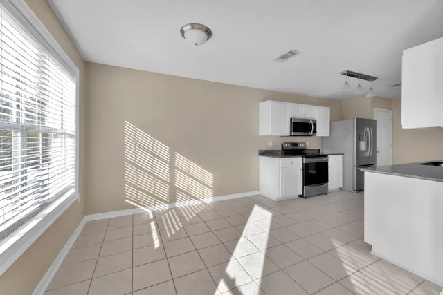 a kitchen with stainless steel appliances granite countertop a stove a sink and white cabinets