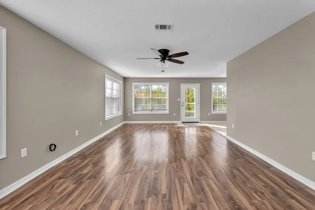 an empty room with wooden floor and windows