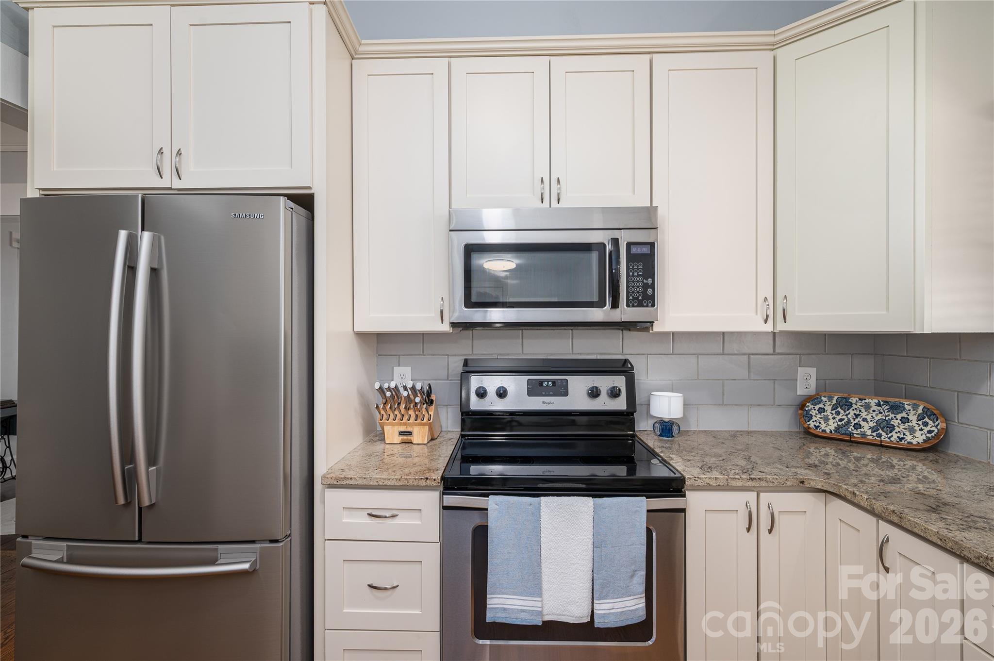 58 Fourth Street Cramerton, NC 28032 - Photo 25 of 44 a kitchen with stainless steel appliances granite countertop a refrigerator stove and white cabinets