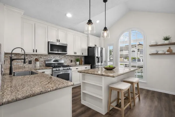 a kitchen with a sink a stove and chairs