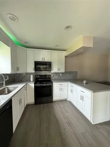 a kitchen with granite countertop white cabinets and stainless steel appliances