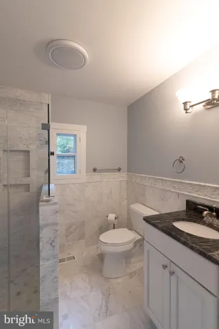 a bathroom with a granite countertop sink a toilet and a mirror